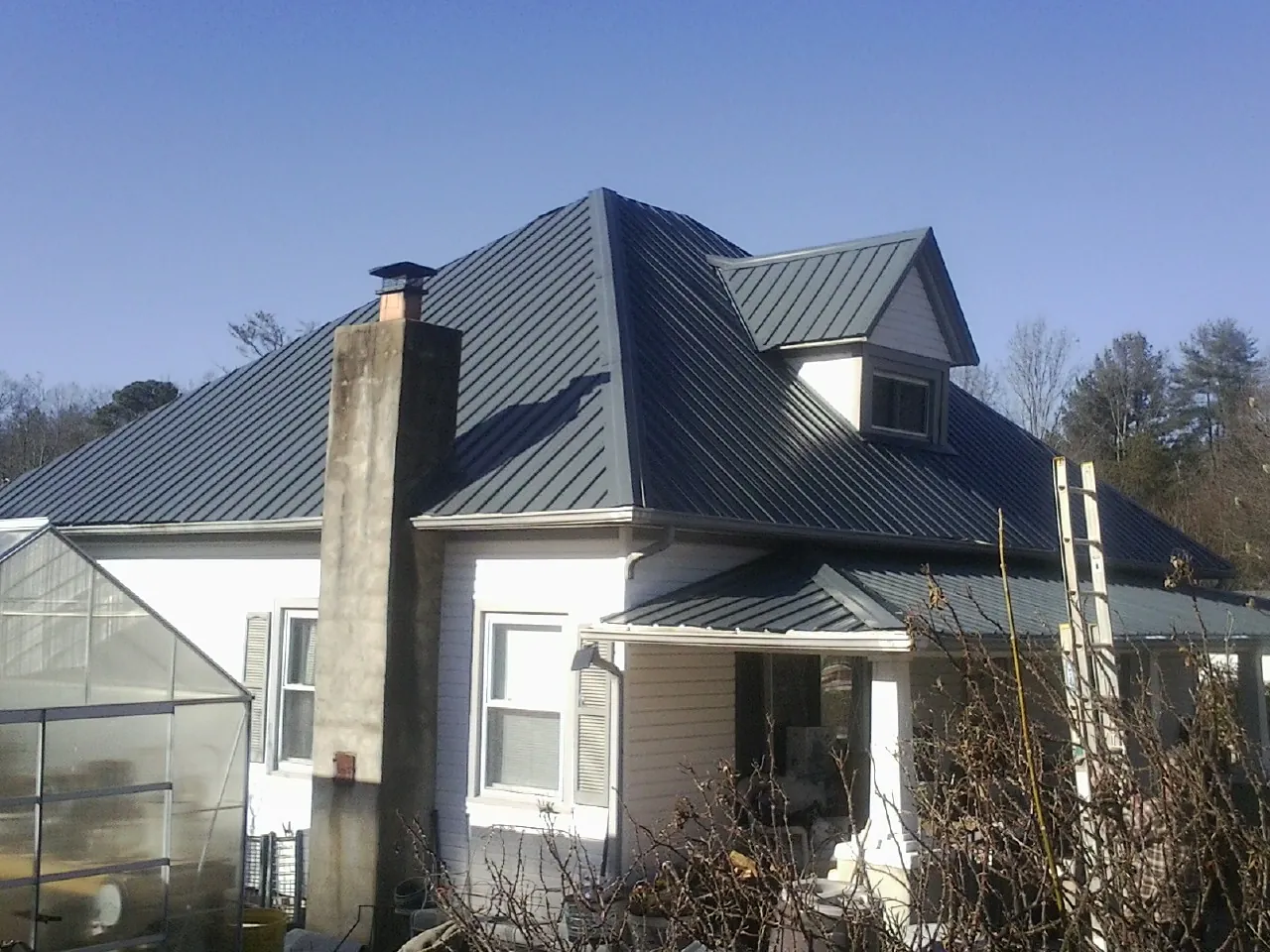 Dark blue standing seam metal roof on a white farmhouse with dormer — Slate & Tile Roof Repair by Roofing Brothers in Leesburg